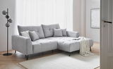 Graues Ecksofa SWING mit Ottomane, dekoriert mit Kissen und Decke, in einem hellen Wohnzimmer, seitliche Perspektive.