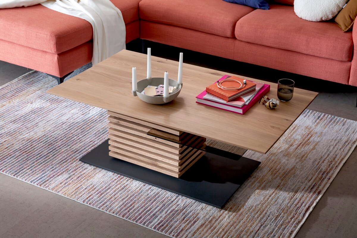 Moderne houten salontafel met gestapeld ontwerp, gefotografeerd van bovenaf, op een tapijt voor een rode bank.
