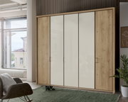 Moderner 5-türiger Drehtürenschrank in Holzoptik mit weißen Fronten, fotografiert aus einer frontalen Perspektive in einem hellen Raum.