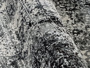 Nahaufnahme eines Designer-Teppichs mit abstraktem Muster in Grautönen, aus seitlicher Perspektive aufgenommen.