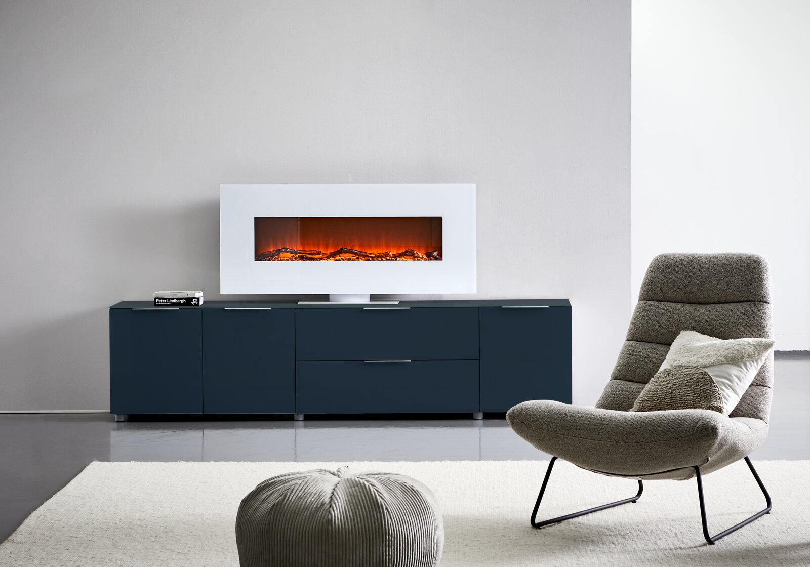 Voleo XL-TV-Lowboard MALIN Frontale Ansicht eines modernen XL-TV-Lowboards in dunklem Blau mit integriertem Elektrokamin, platziert in einem stilvollen Wohnzimmer.