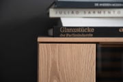 Nahaufnahme eines Highboards aus Holz mit Büchern darauf, seitliche Perspektive