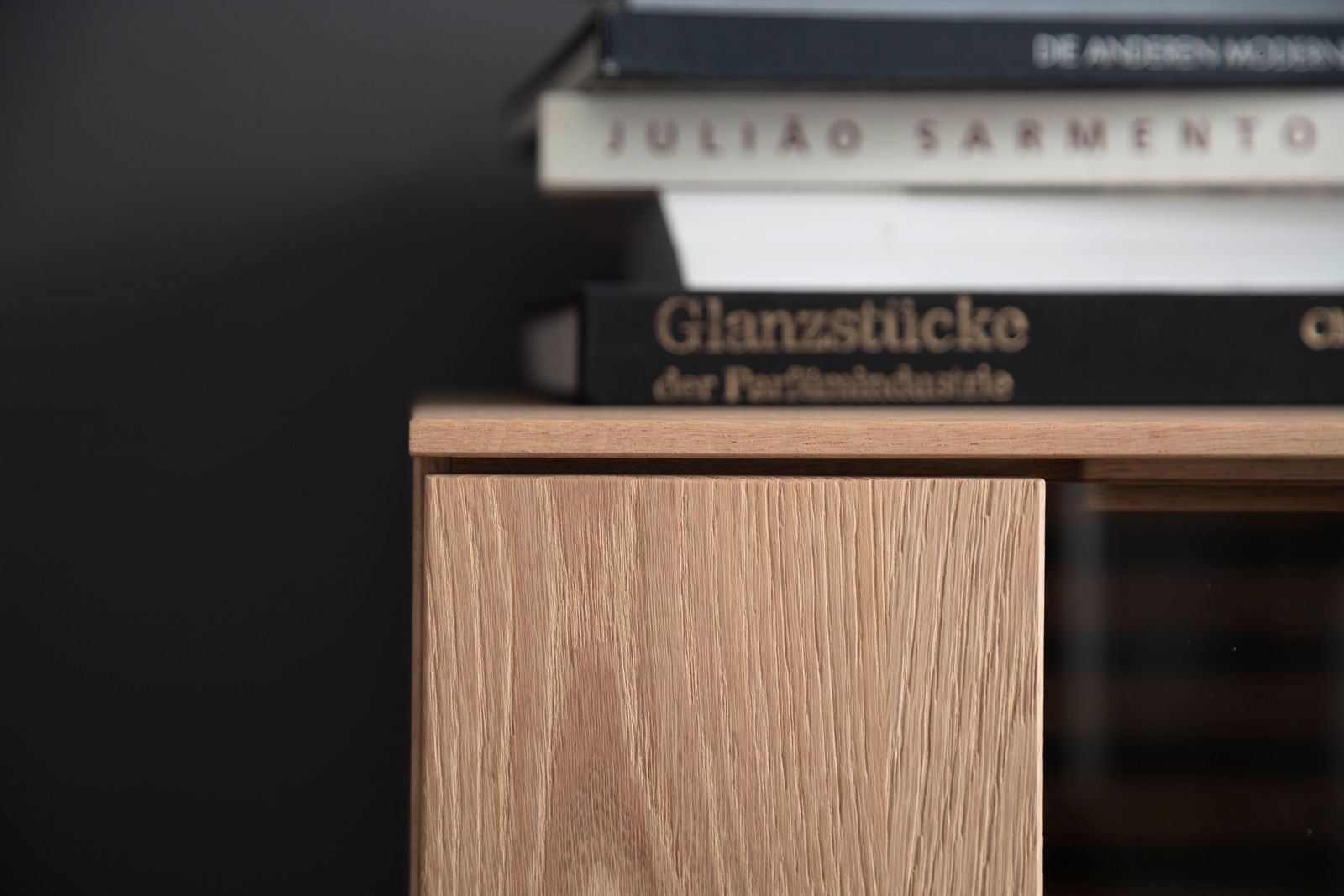 Nahaufnahme eines Highboards aus Holz mit Büchern darauf, seitliche Perspektive