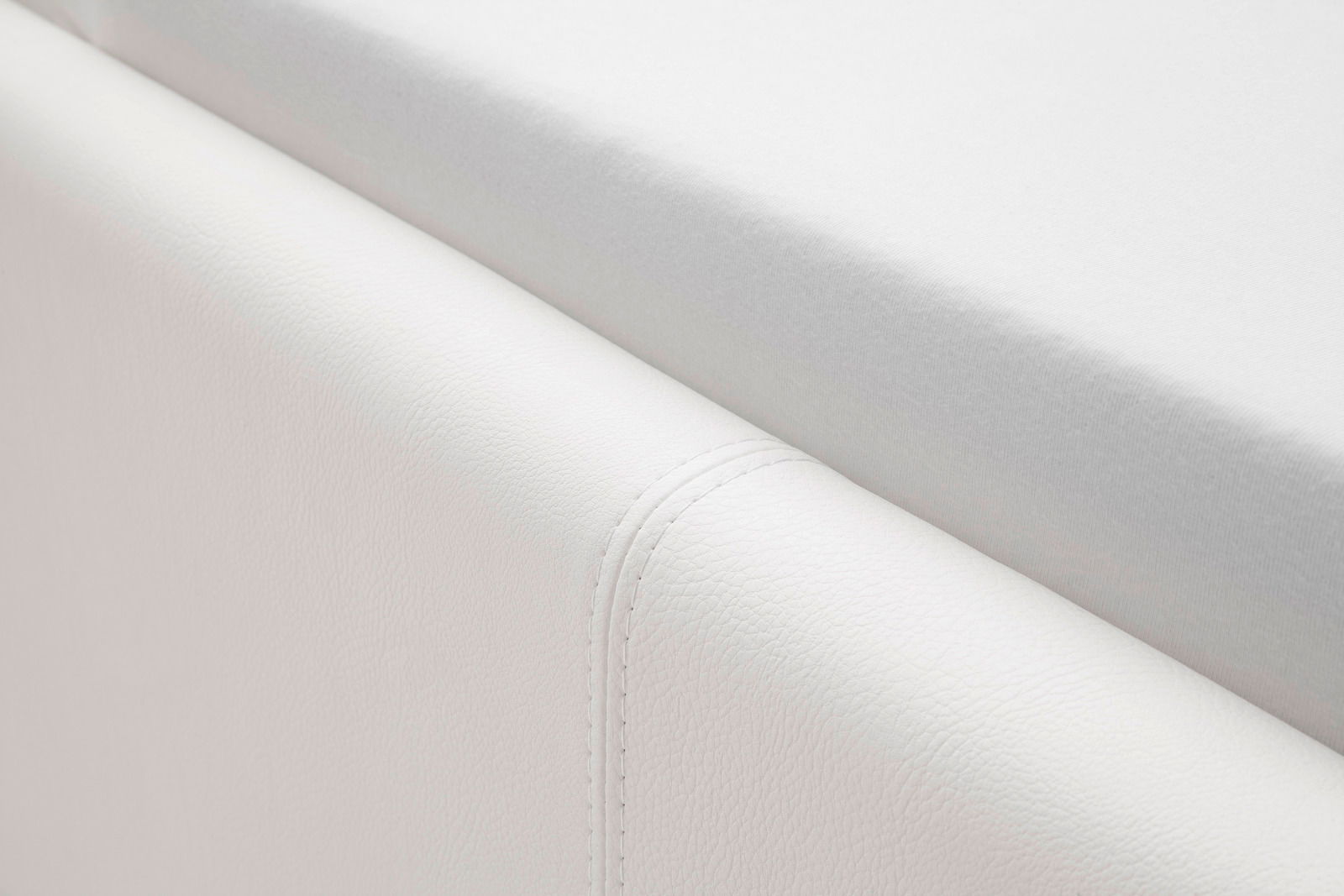 Nahaufnahme eines weißen Polsterbetts mit sichtbarer Naht, seitliche Perspektive.