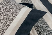 Nahaufnahme einer Bettwäsche mit Leopardenmuster und Streifen in Schwarz, Weiß und Beige.