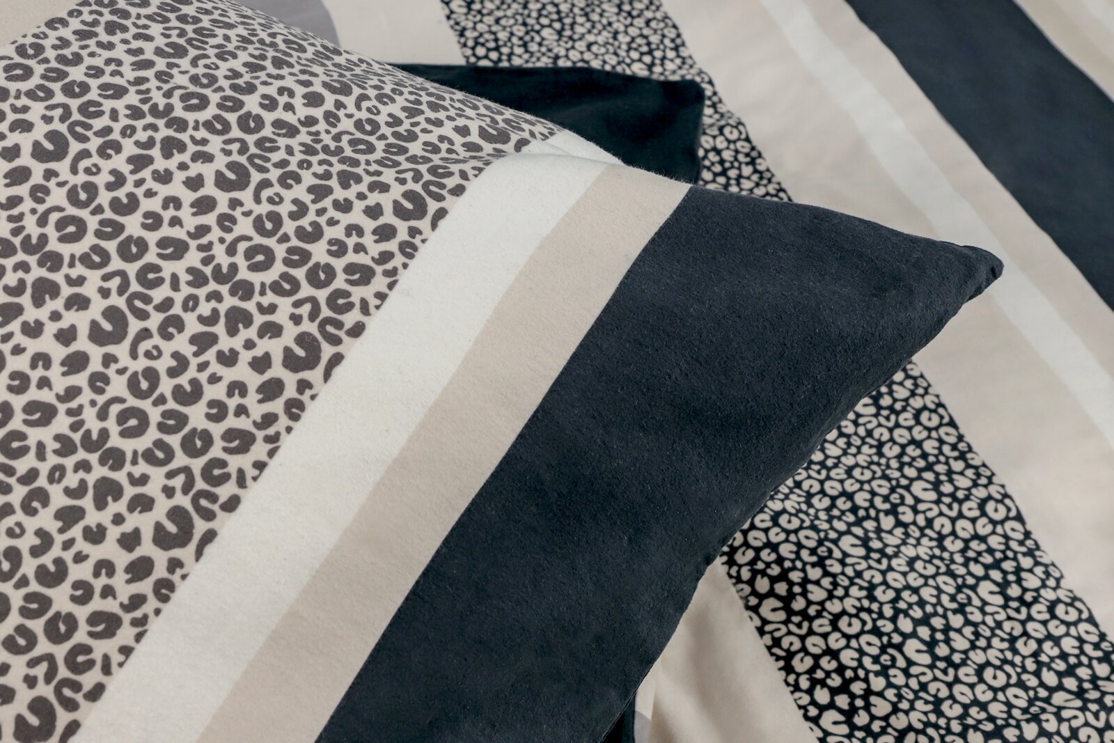 Nahaufnahme einer Bettwäsche mit Leopardenmuster und Streifen in Schwarz, Weiß und Beige.