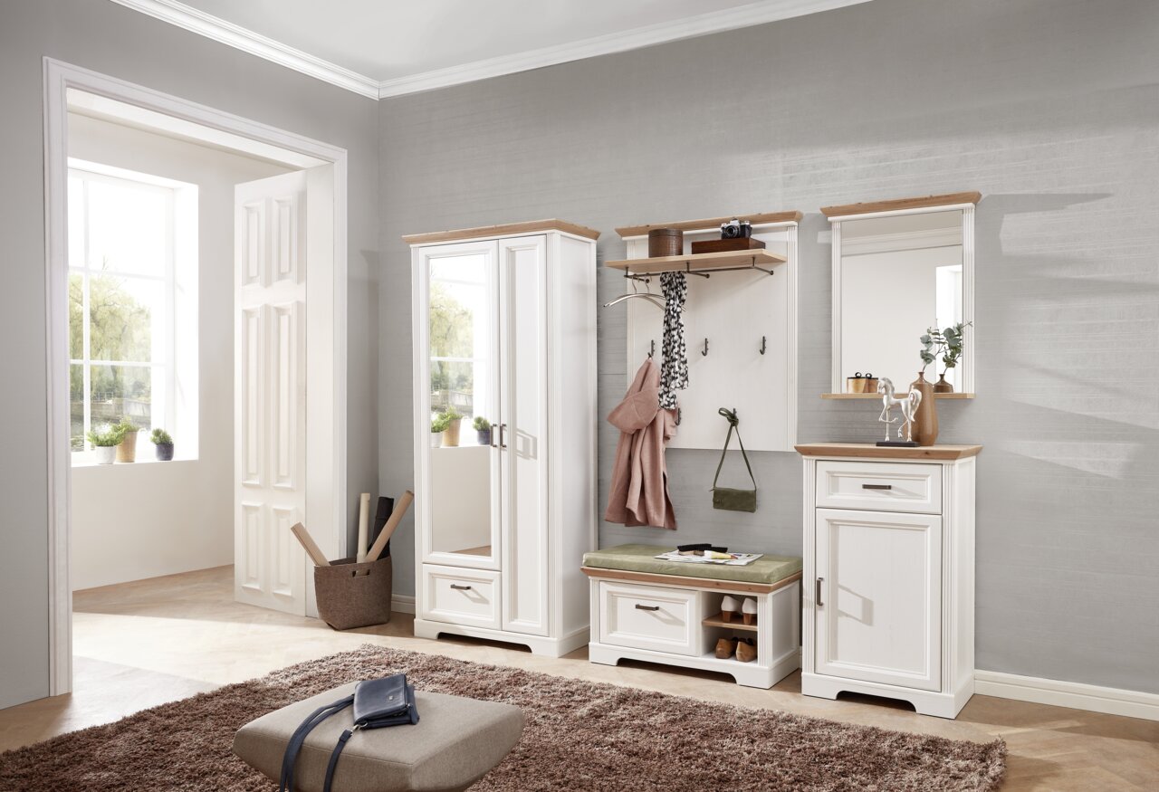 Garderoben-Set in einem modernen Flur mit weißem Holz und naturfarbenen Akzenten, bestehend aus einem hohen Schrank mit Spiegel, einer Sitzbank mit Stauraum und einem Wandpaneel mit Haken, aus der Perspektive des Raumes fotografiert.