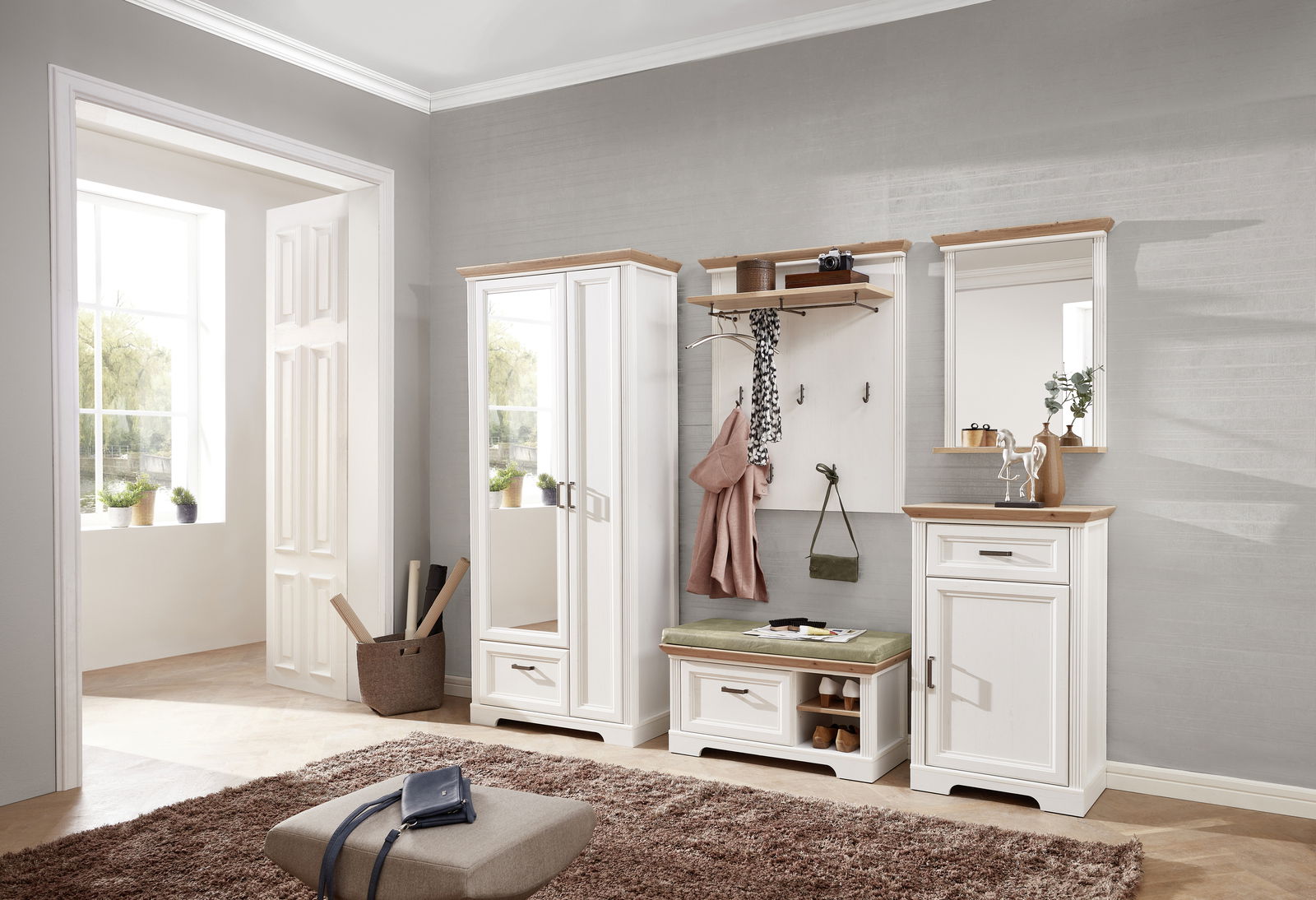Garderoben-Set in einem modernen Flur mit weißem Holz und naturfarbenen Akzenten, bestehend aus einem hohen Schrank mit Spiegel, einer Sitzbank mit Stauraum und einem Wandpaneel mit Haken, aus der Perspektive des Raumes fotografiert.