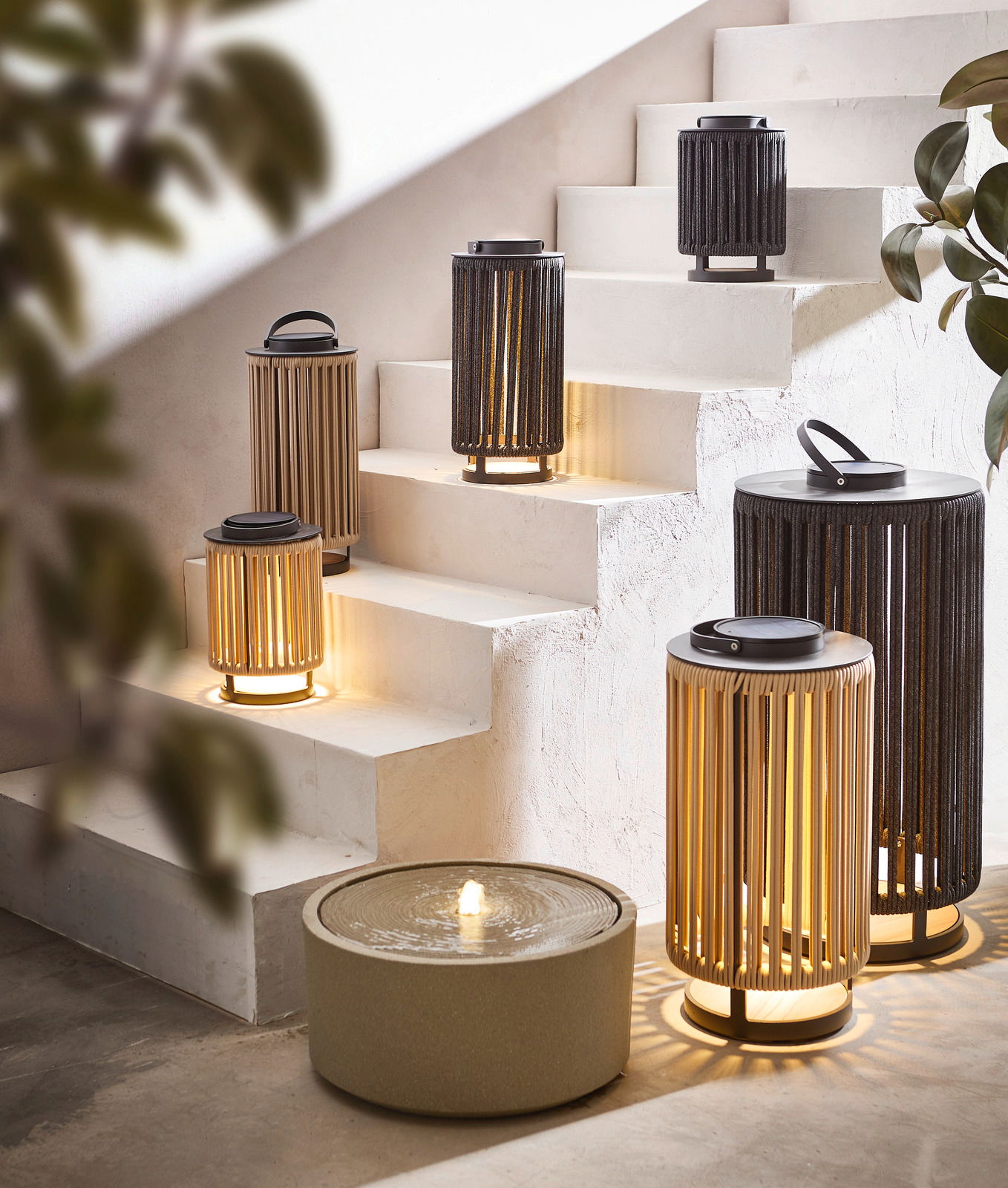 Ambia Garden Solarlampe LUMIN Mehrere Solarlampen in verschiedenen Größen auf einer Treppe, beleuchtet und in einer modernen Umgebung platziert, seitliche Perspektive.