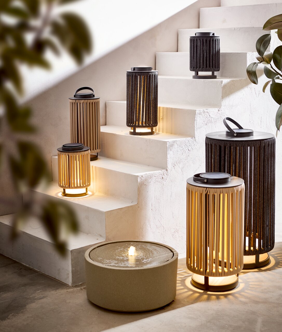 Ambia Garden Solarlampe LUMIN Mehrere Solarlampen in verschiedenen Größen auf einer Treppe, beleuchtet und in einer modernen Umgebung platziert, seitliche Perspektive.