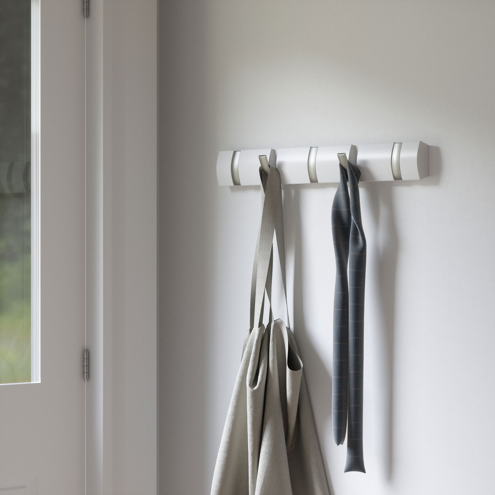 Wandgarderobe mit mehreren Haken, an denen Taschen und ein Schal hängen, seitliche Perspektive