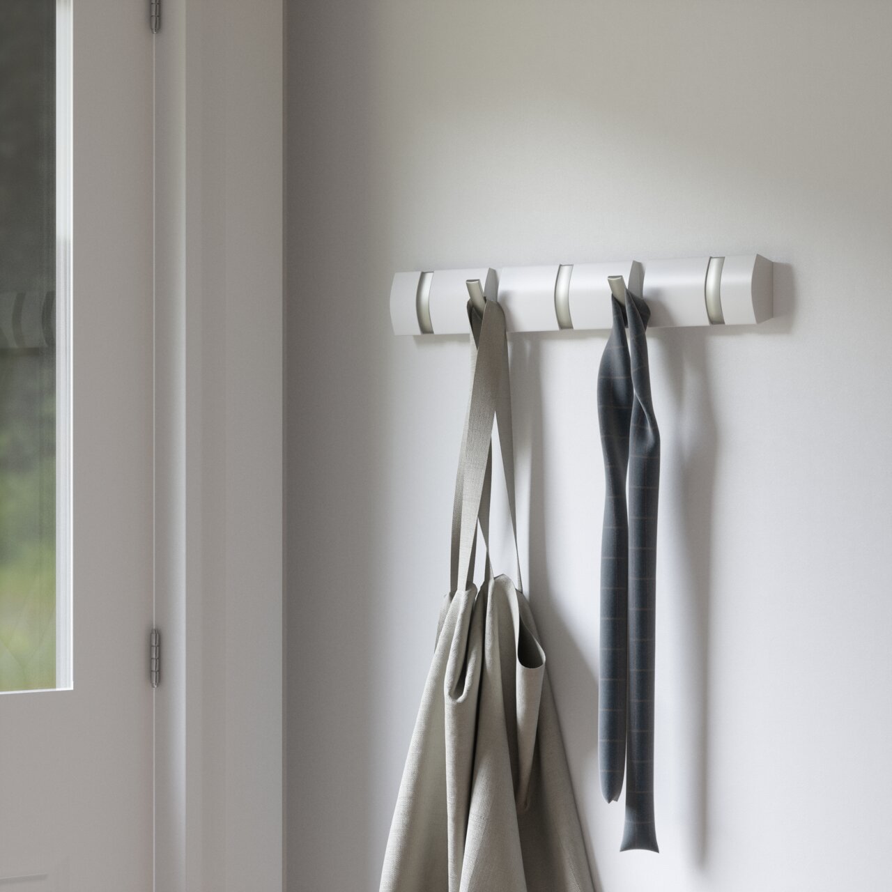 Wandgarderobe mit mehreren Haken, an denen Taschen und ein Schal hängen, seitliche Perspektive