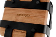Close-up schuin zijaanzicht van een evasoIo bamboe plank/serveerplank met zwarte metalen beugels en zichtbaar logo op witte achtergrond