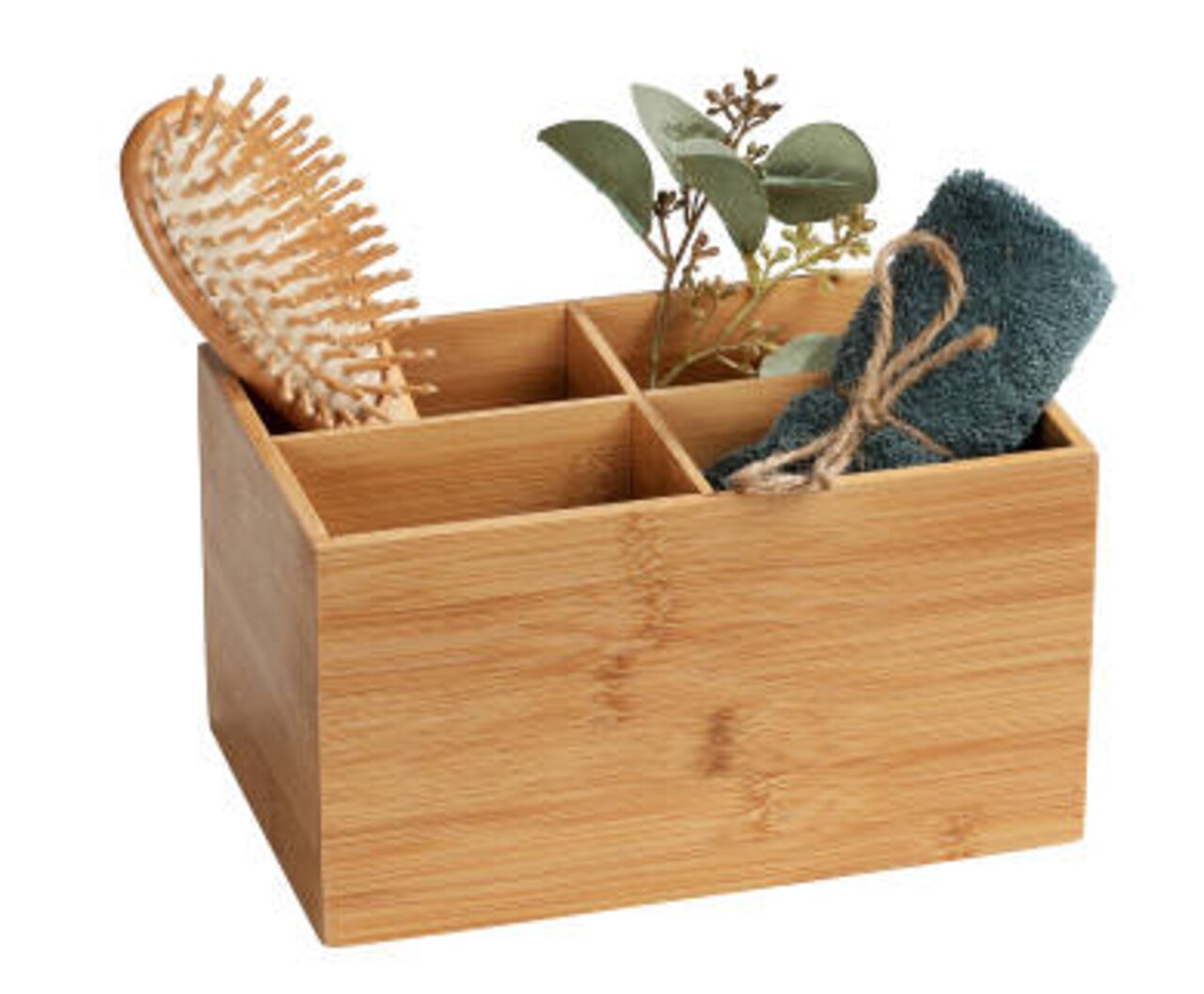 Bambus Box mit vier Fächern, gefüllt mit einer Haarbürste, einem Handtuch und Pflanzen, aus schräger Perspektive fotografiert.