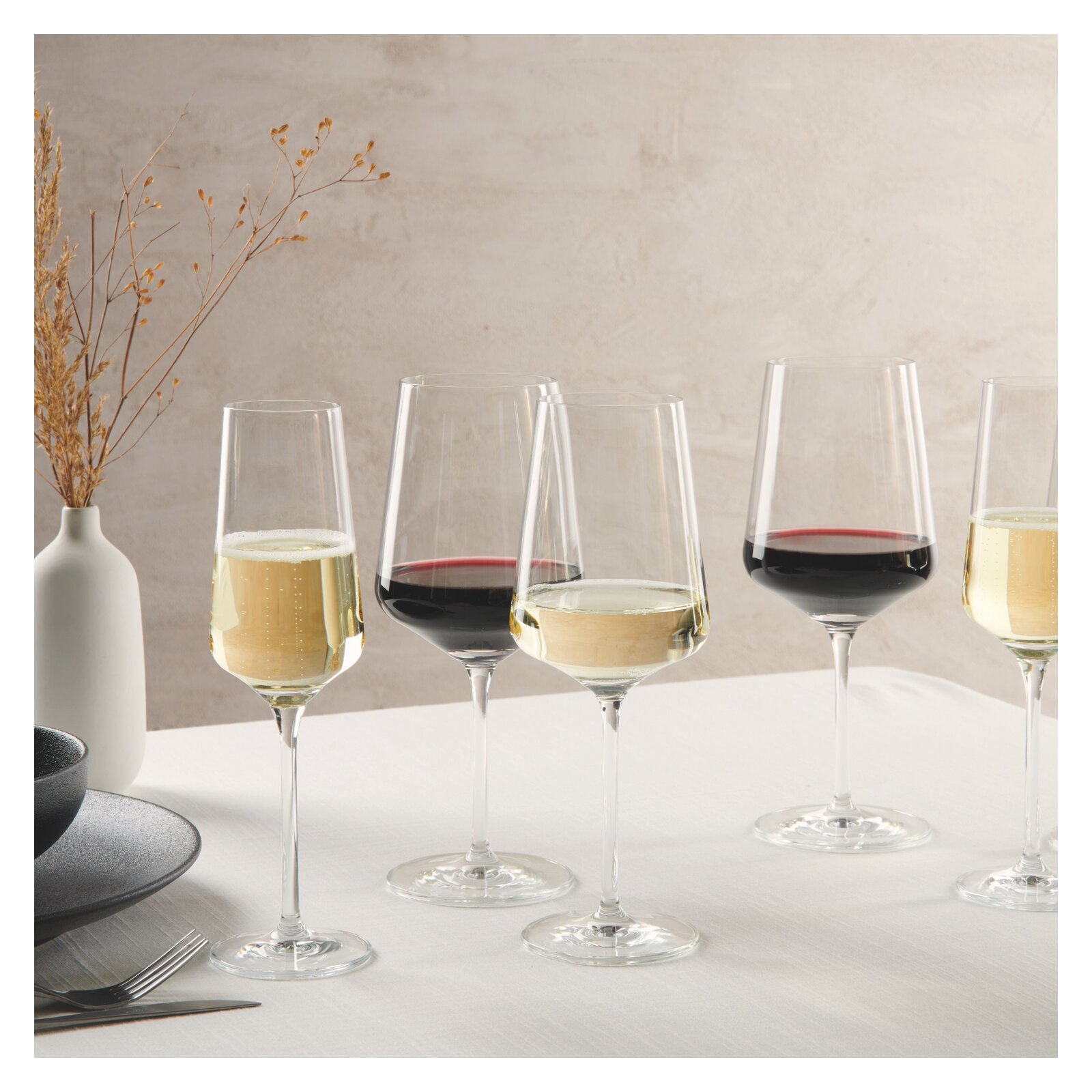 Eine elegante Anordnung von Kelchgläsern mit Rot- und Weißwein auf einem Tisch, seitliche Perspektive.