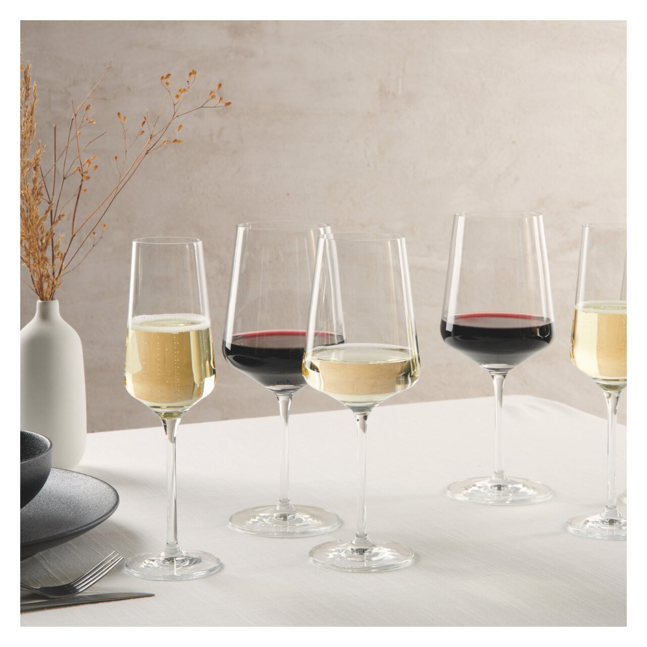 Ritzenhoff Set van 18 kelkglaasjes LICHTWEISS Eine elegante Anordnung von Kelchgläsern mit Rot- und Weißwein auf einem Tisch, seitliche Perspektive.