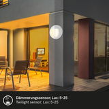 Akku-Außenwandleuchte an einer Hauswand bei Dämmerung, seitliche Perspektive