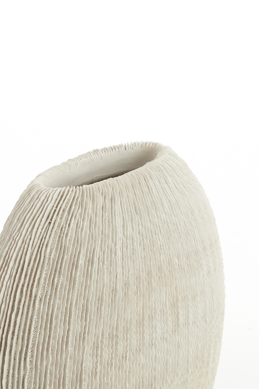 Nahaufnahme einer cremeweißen, geriffelten Keramikvase mit ovaler Öffnung, schräg von oben fotografiert vor weißem Hintergrund.