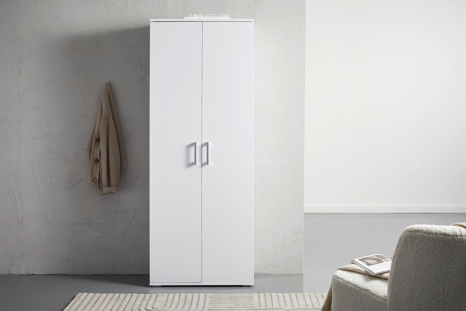 Weißer XL-Schuhschrank mit zwei Türen, frontal fotografiert, neben einer grauen Wand mit hängendem Mantel.