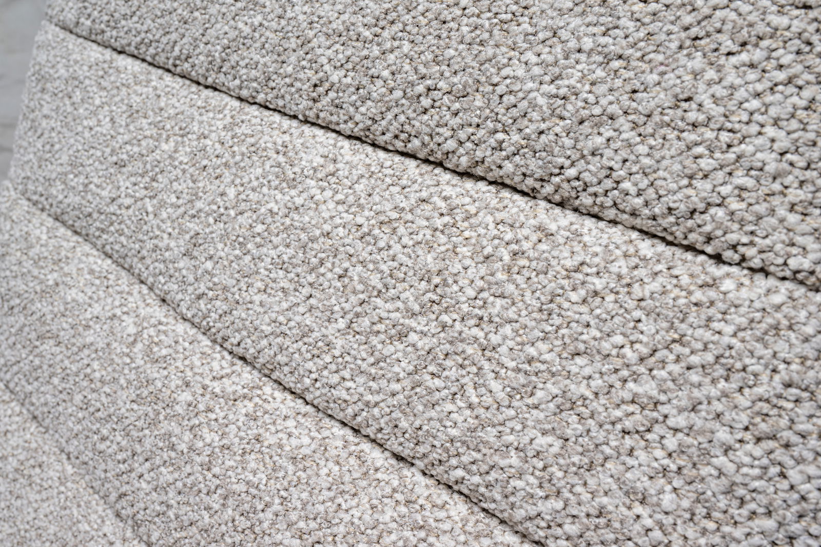 Nahaufnahme der strukturierten, hellgrauen Polsterung eines Drehstuhls in seitlicher Perspektive.