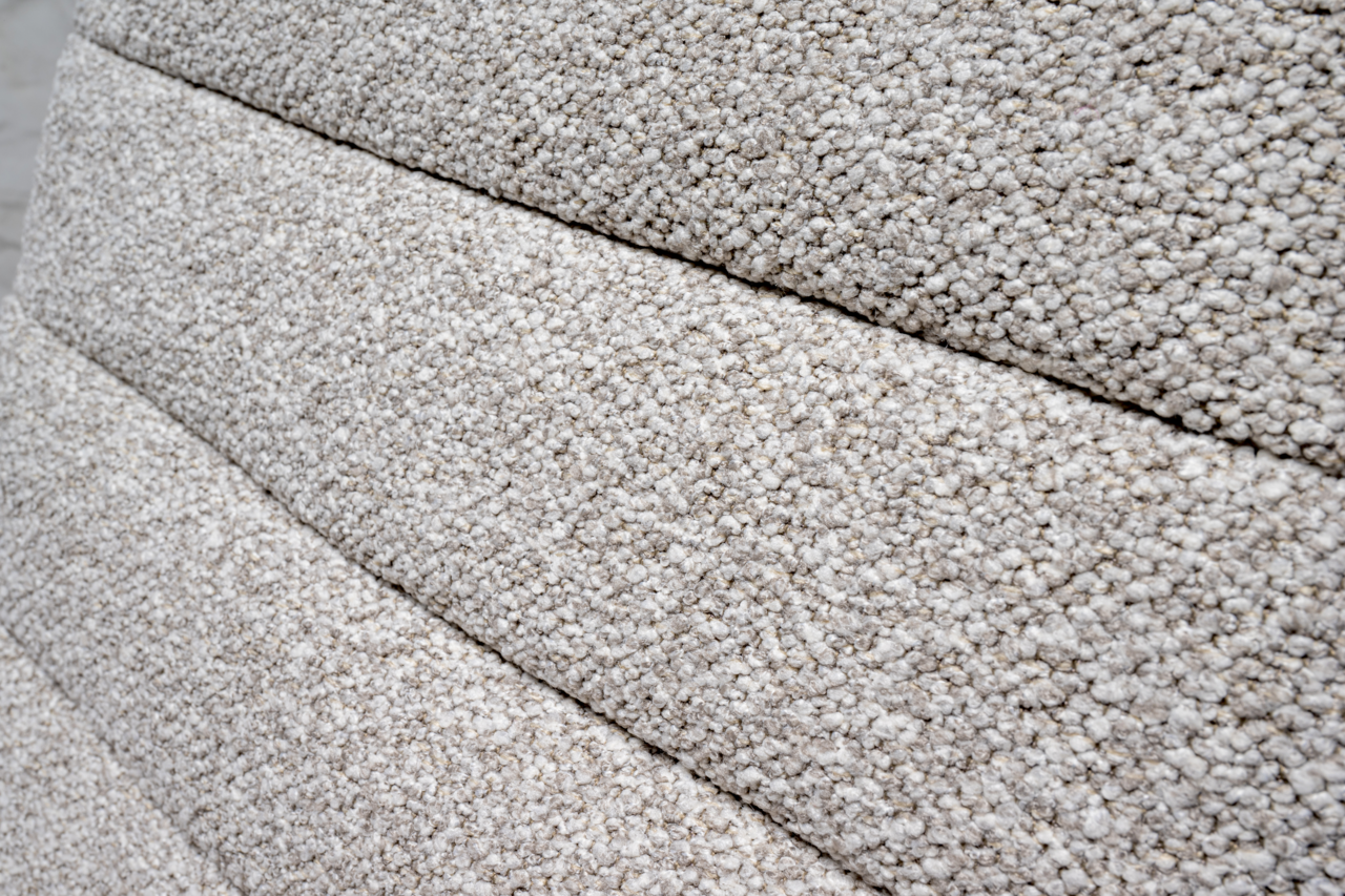 Nahaufnahme der strukturierten, hellgrauen Polsterung eines Drehstuhls in seitlicher Perspektive.