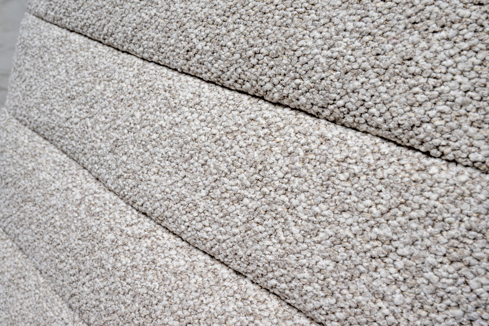 Nahaufnahme der strukturierten, hellgrauen Polsterung eines Drehstuhls in seitlicher Perspektive.