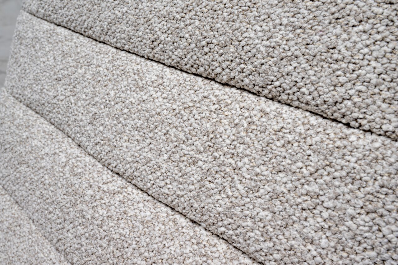 Nahaufnahme der strukturierten, hellgrauen Polsterung eines Drehstuhls in seitlicher Perspektive.