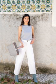 Frau in weißer Hose und grauem Top hält einen grauen carrybag XS in der Hand, seitliche Perspektive.