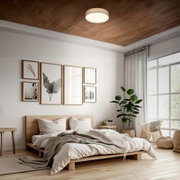Modernes Schlafzimmer mit rundem Deckenleuchten-Panel in Holzoptik an der Decke, Blick aus leicht erhöhter Perspektive schräg von vorn auf das Bett und den Raum