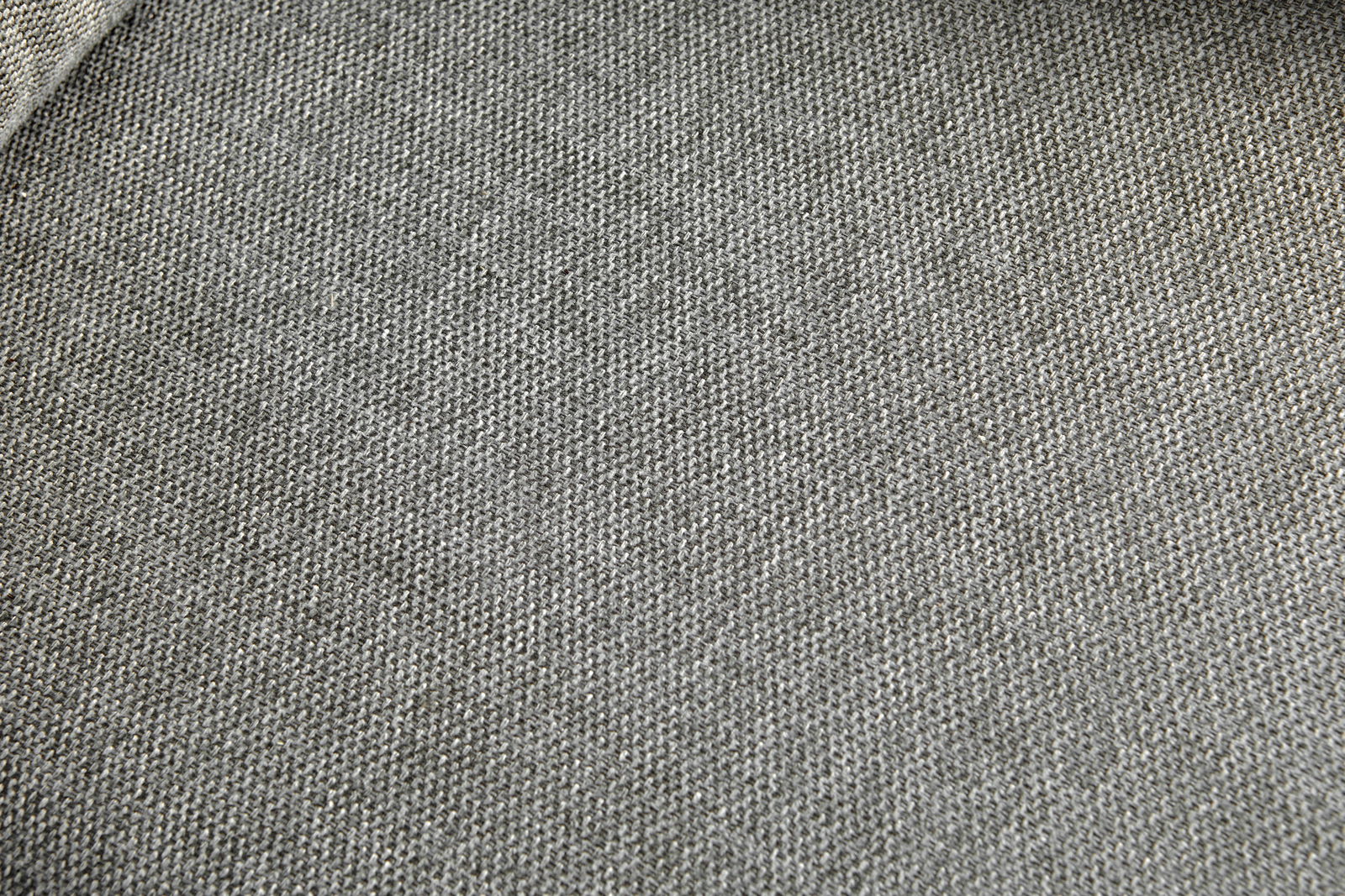 Nahaufnahme eines grauen Stoffbezugs mit feiner Webstruktur, perspektivisch von oben fotografiert.