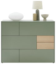 Frontansicht eines modernen, grünen Highboards mit Holzdetails, dekoriert mit einer Lampe, einer Vase und einer Schale.