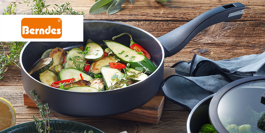 Eine Pfanne mit bunten Gemüse auf einem rustikalen Holztisch. Berndes-Logo sichtbar.