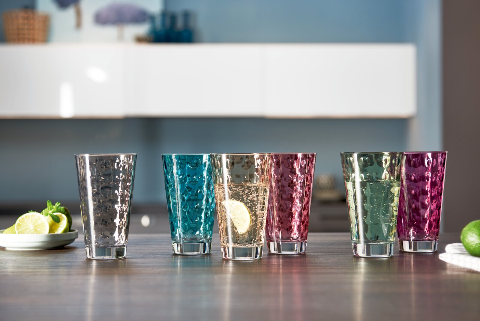 Farbiges Becherset mit sechs 300ml Gläsern in verschiedenen Farben, frontal auf einem Tisch präsentiert.
