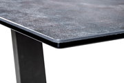 Nahaufnahme einer Couchtisch-Ecke mit dunkler, strukturierter Tischplatte und stabilen, schwarzen Beinen.