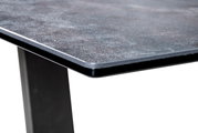 Nahaufnahme einer Couchtisch-Ecke mit dunkler, strukturierter Tischplatte und stabilen, schwarzen Beinen.