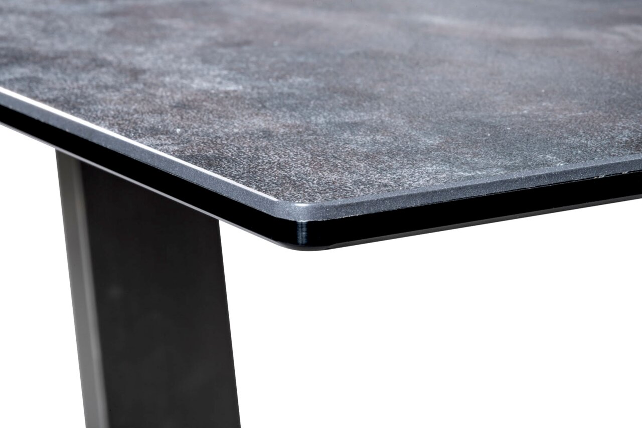 Nahaufnahme einer Couchtisch-Ecke mit dunkler, strukturierter Tischplatte und stabilen, schwarzen Beinen.