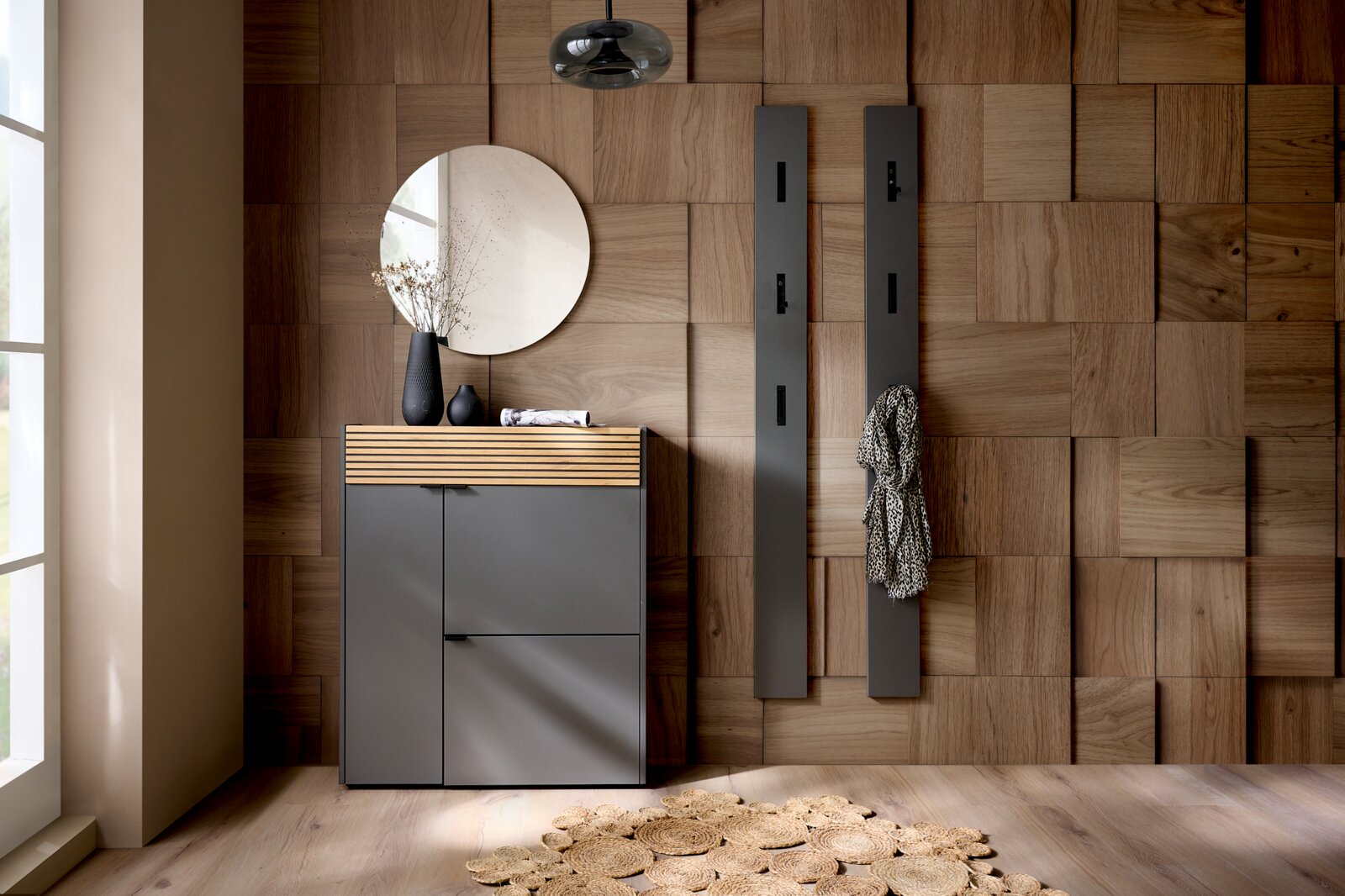 Voleo Garderoben-Set RIO Garderoben-Set in Graphit mit modernem Design, bestehend aus einem Schrank mit Holzdetails und zwei Wandpaneelen mit Haken, aus der Perspektive eines hellen Raumes mit Holzboden und Wandverkleidung.
