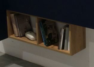 Hängeregal aus Holz mit zwei Fächern, gefüllt mit Büchern und einem kleinen Dekorationsobjekt, seitliche Perspektive