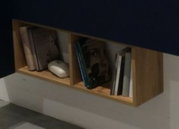 Houten hangplank met twee vakken, gevuld met boeken en een klein decoratiestuk, zijaanzicht