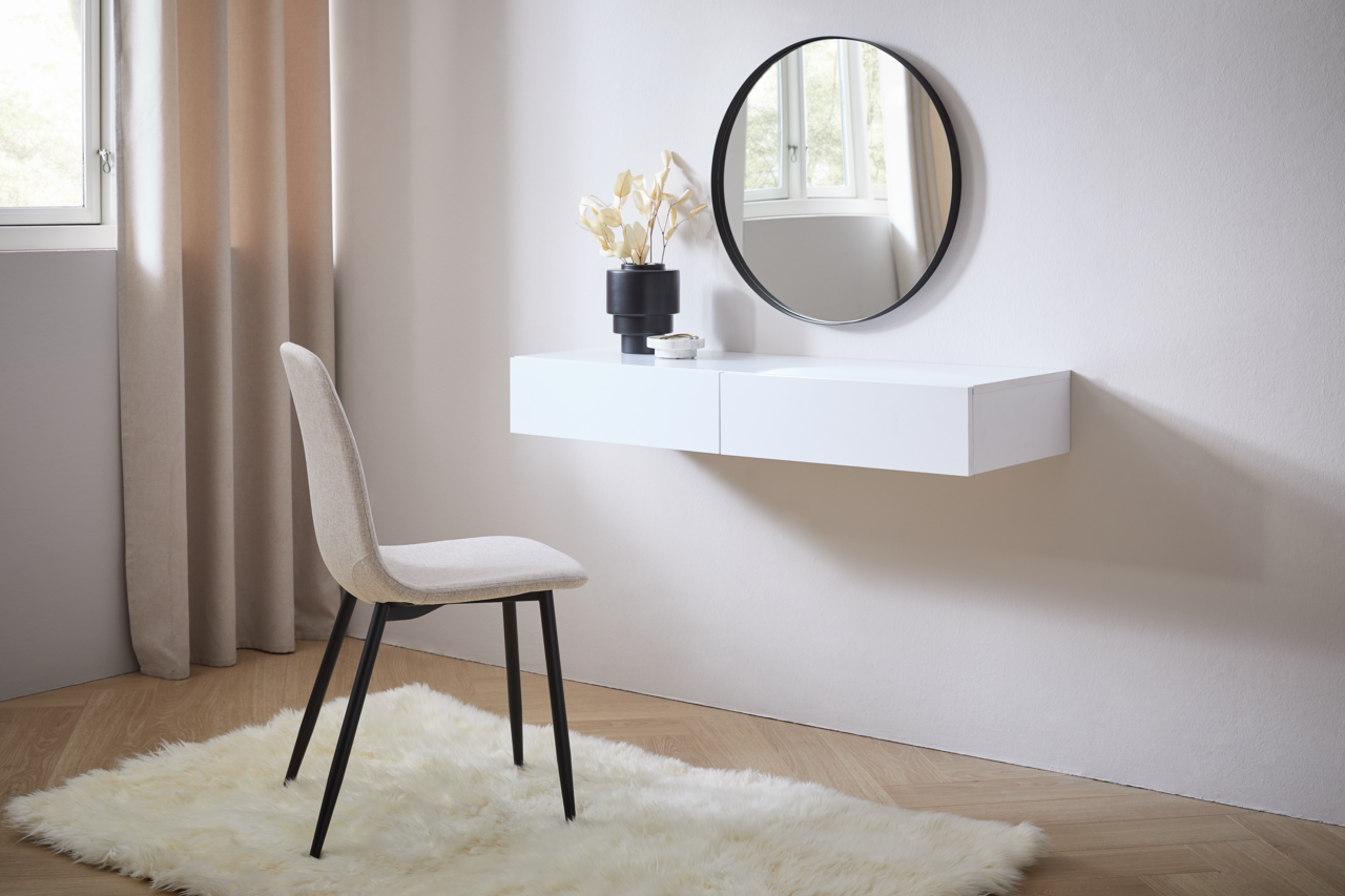 Moderne Wandkonsole in Weiß mit rundem Spiegel darüber, seitliche Perspektive. Dekoriert mit einer Vase und einem kleinen Objekt, daneben ein beiger Stuhl auf einem flauschigen Teppich.