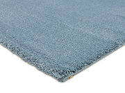 Perspektivische Ansicht eines blauen Uni-Teppichs mit weicher, flauschiger Oberfläche.