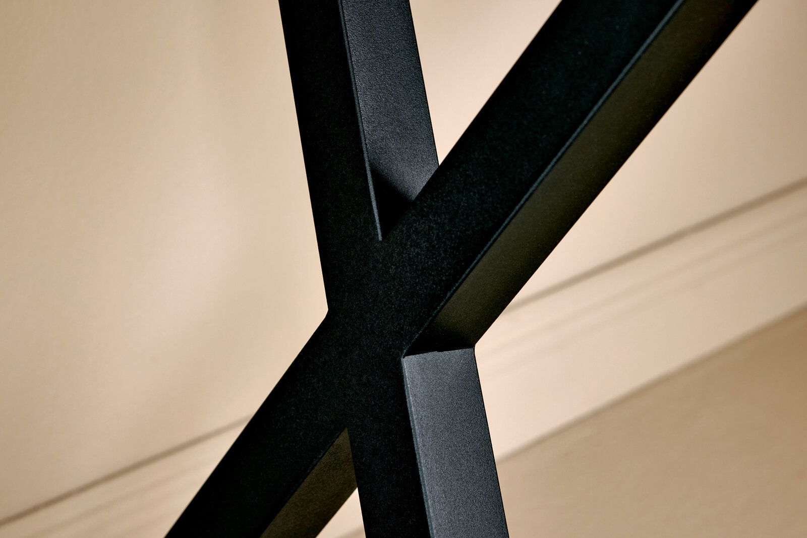 Nahaufnahme eines schwarzen Metallgestells in X-Form, Teil einer Eck-Schreibtisch-Kombination, seitliche Perspektive