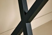 Nahaufnahme eines schwarzen Metallgestells in X-Form, Teil einer Eck-Schreibtisch-Kombination, seitliche Perspektive