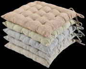 Een stapel van vier zitkussens in verschillende kleuren, van boven naar beneden: beige, groen, grijs en crème, gezien vanaf de zijkant