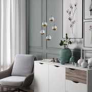 Moderne LED-Hängeleuchte von Dieter Knoll mit fünf kugelförmigen, gold- und silberfarbenen Lampenschirmen, hängend in einem stilvoll eingerichteten Wohnzimmer. Perspektive: seitlich.