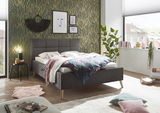 Modernes Polsterbett in einem stilvoll eingerichteten Schlafzimmer, seitliche Perspektive, mit dekorativen Kissen und Decken.