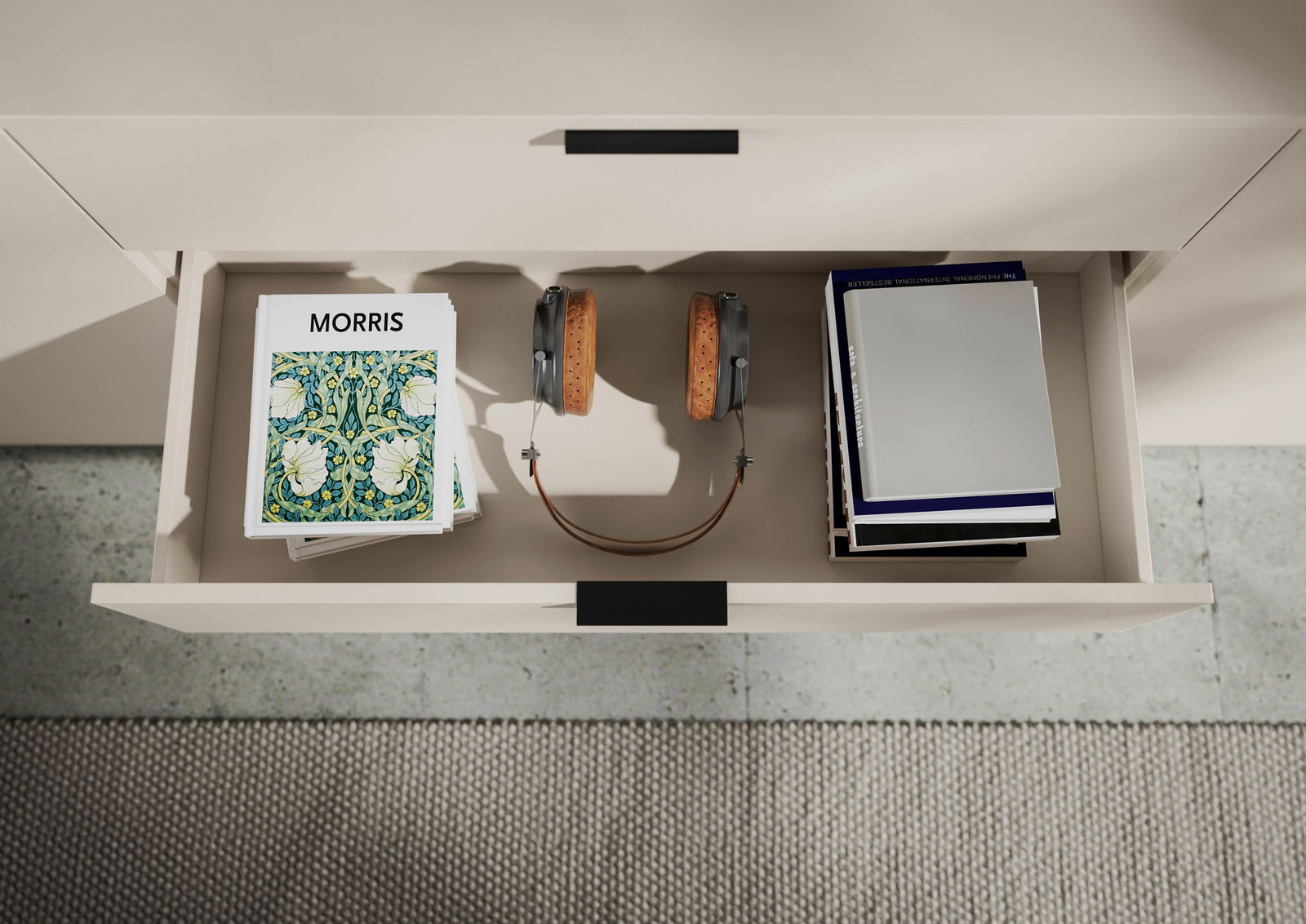 Offene Schublade eines XL-Sideboards mit Büchern, Kopfhörern und Zeitschriften, von oben betrachtet.