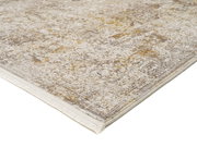 Designer Teppich in Beige- und Goldtönen mit Fransen, perspektivisch von der Seite fotografiert.