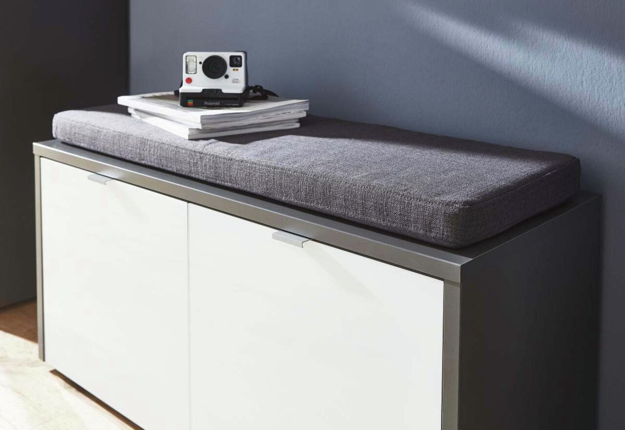 Graues Sitzkissen auf einem weißen Schrank, seitliche Perspektive