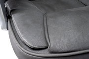 Nahaufnahme der Sitzfläche eines Chefsessels aus grauem Leder mit sichtbaren Nähten, seitliche Perspektive.